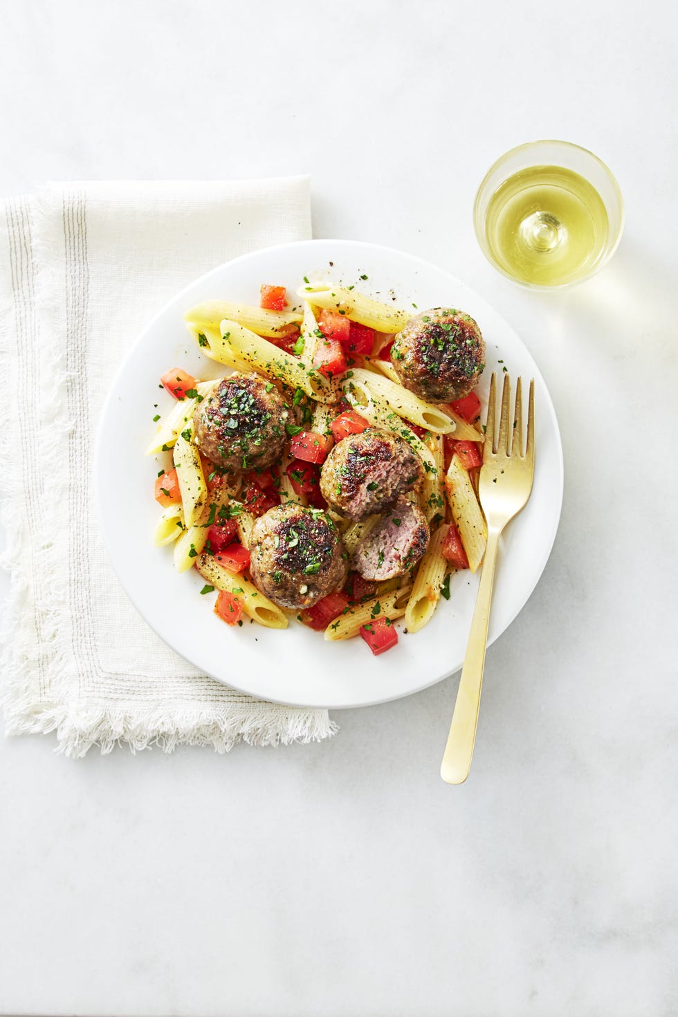grilled lamb meatballs with penne pasta on a white plate