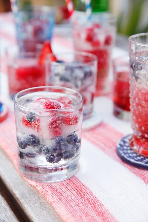 sparkling water or champagne with fresh strawberries and blueberries in a clear glass