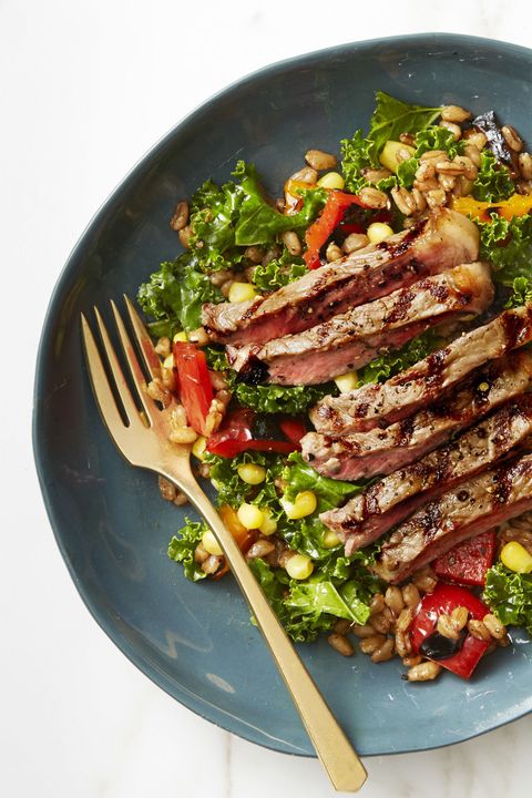 summer farro salad with grilled steak on a blue plate