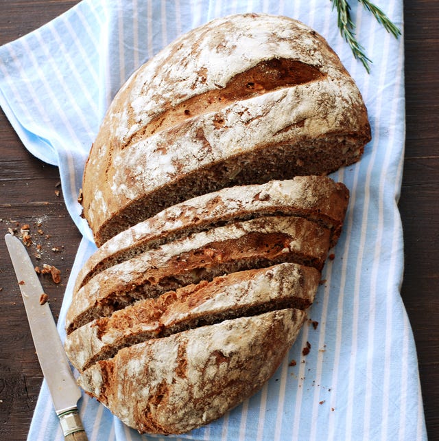 best bread baking cloche a loaf of partially sliced bread on a kitchen towel