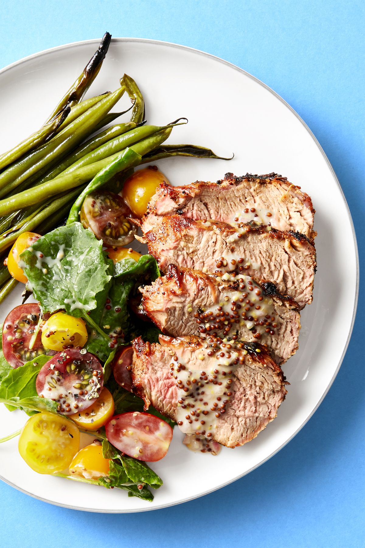 grilled pork tenderloin with green beans and colorful tomatoes