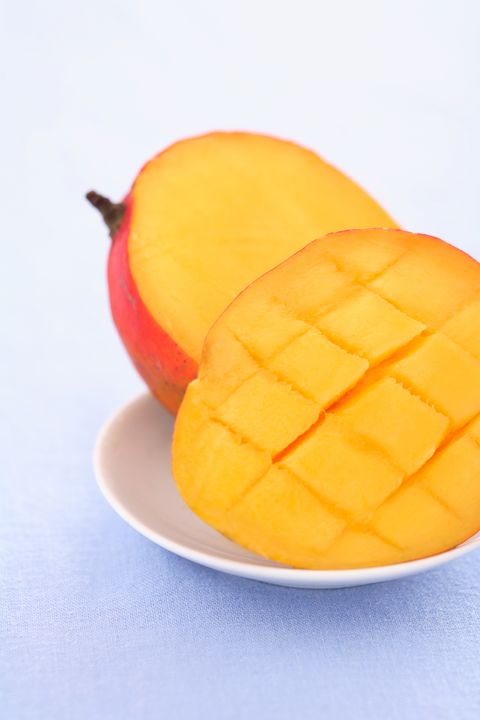 mango cut in half on a white plate and blue backdrop