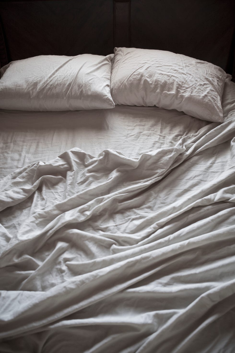 an unmade bed with white sheets