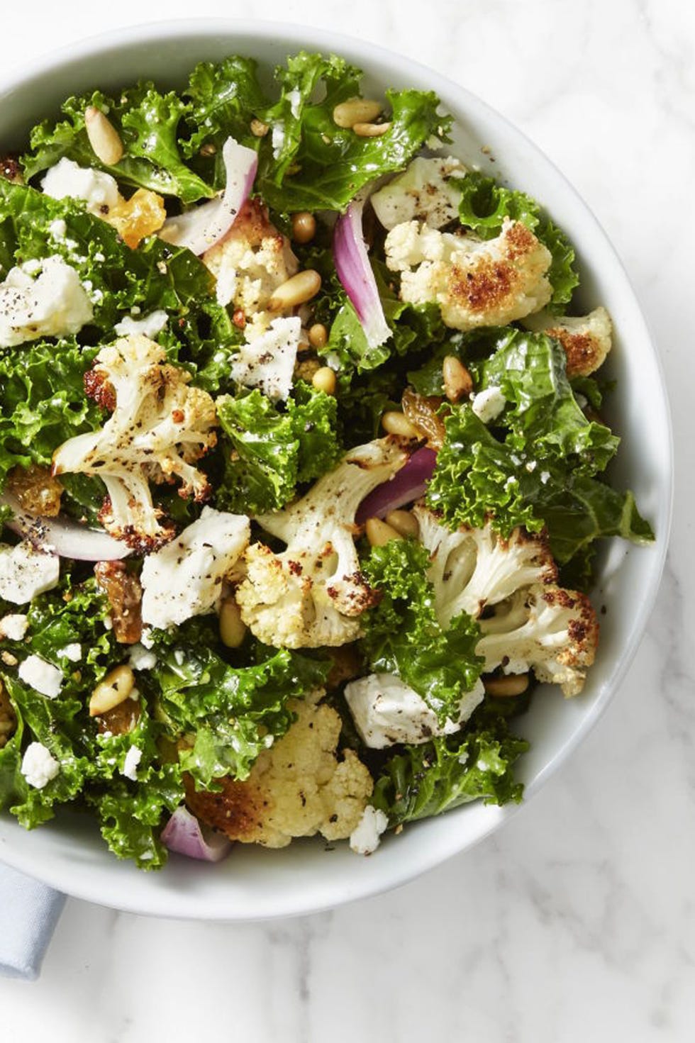 this kale and roasted cauliflower salad is brought to life with pine nuts, golden raisins, feta cheese and a drizzle of lemon juice