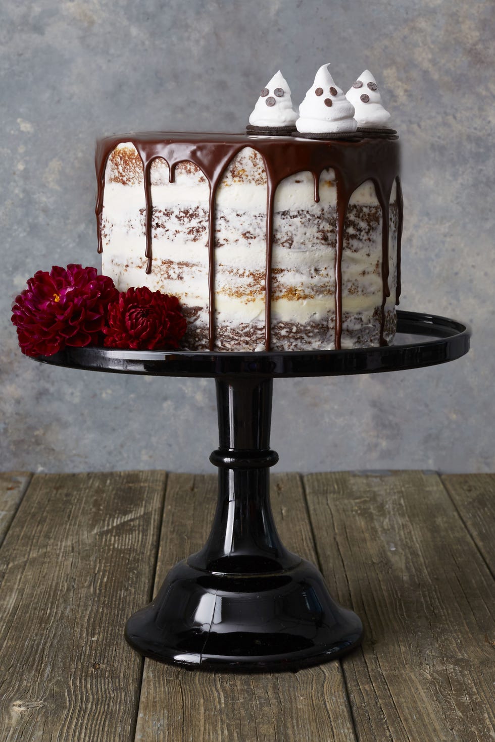 a white frosted cake with chocolate drizzled on top and candied ghosts
