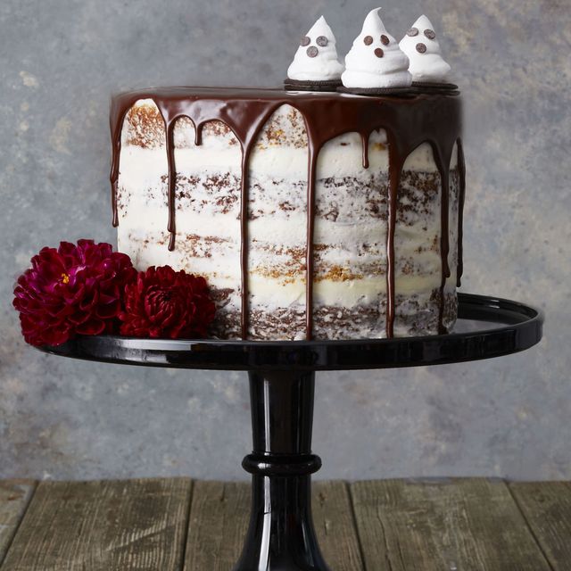a white frosted cake with chocolate drizzled on top and candied ghosts