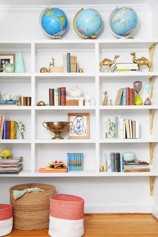Even ordinary objects, like globes, become standout collectibles when grouped in threes. Toys, books, and brass knickknacks add to the eclectic vibe.