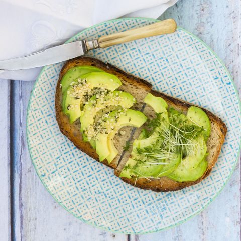 avocado toast with sprouts and chia seeds on a blue plate on a blue wooden table