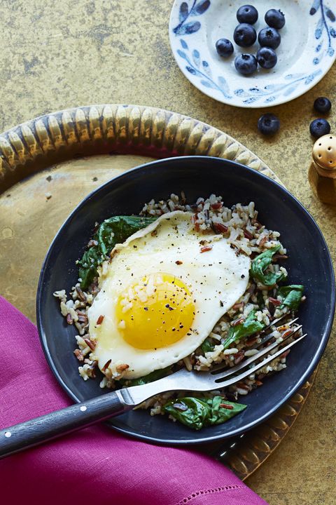 mediterranean diet rice medley with a fried egg on a black plate