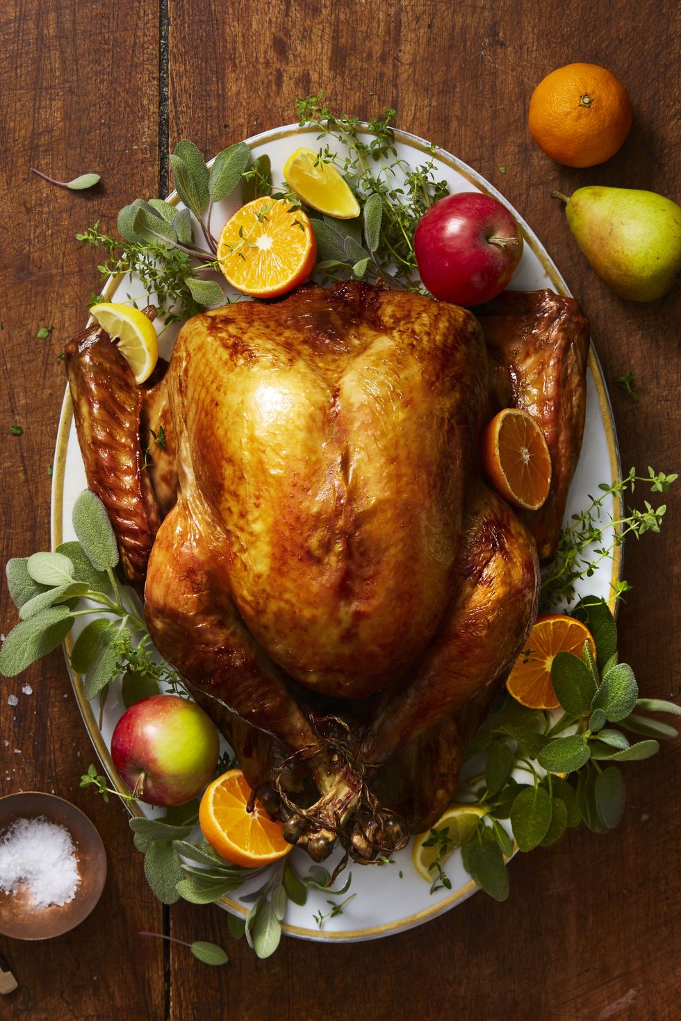 golden herb roasted turkey on a platter with decorative fruit