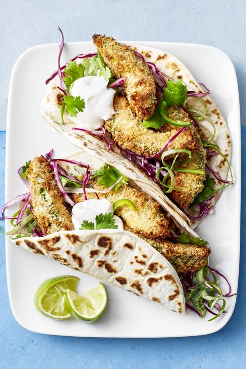 fried avocado tacos with limes on a white platter