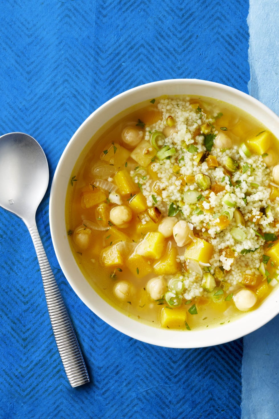 butternut squash and white bean soup in a bowl with spoon on the side