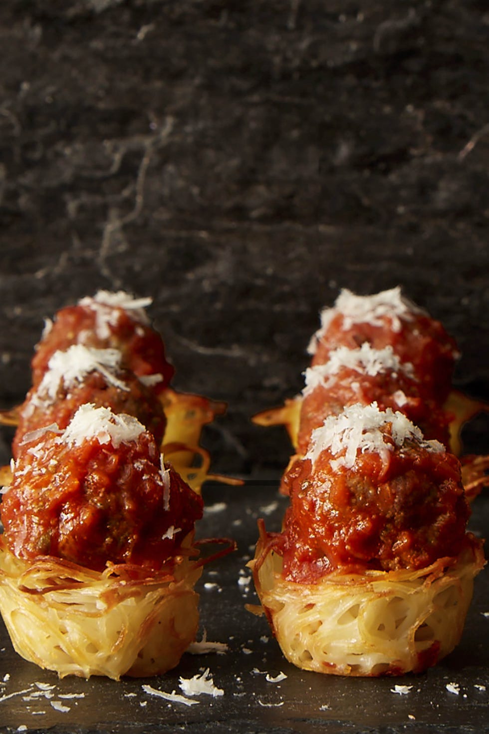 spaghetti and meatball nests with parmesan cheese on top