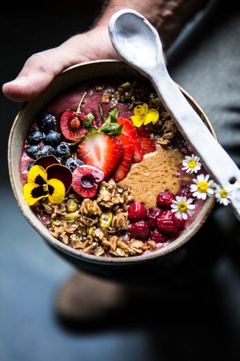 a bowl of peanut butter acai bowl with granola, berries, and flowers