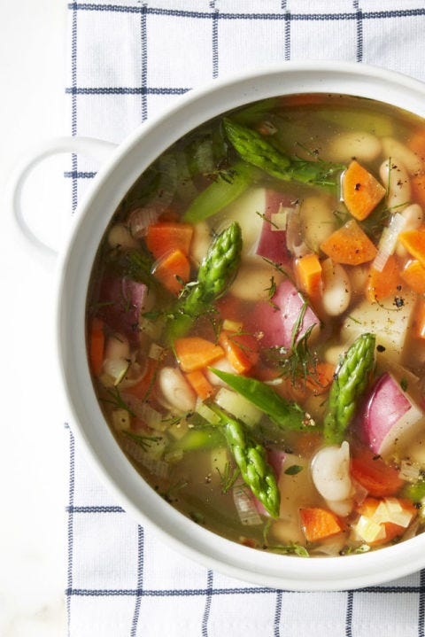 a bowl of spring minestrone soup with asparagus, carrot,  and potato