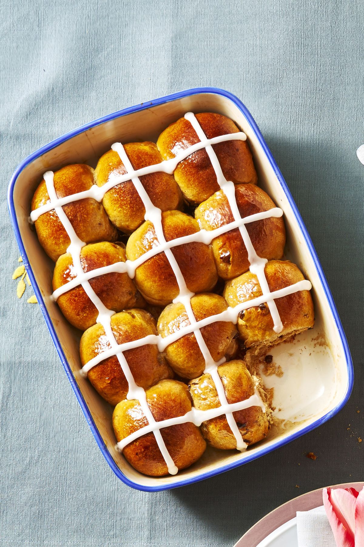 iced hot cross buns in a blue baking dish
