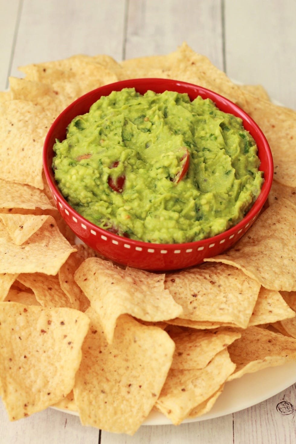 a red bowl of guacamole and chips