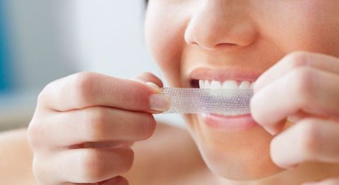 woman using teeth whitening strips