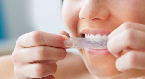 Teeth whitening strips woman using teeth whitening strips