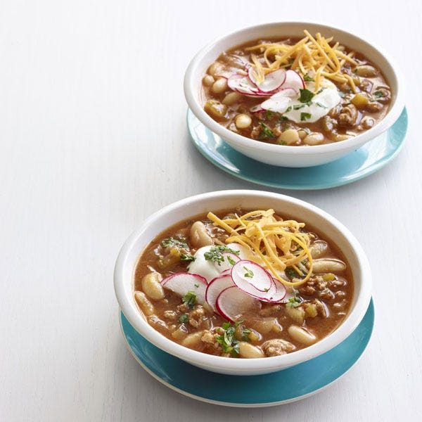 slow cooker turkey pumpkin chili with cheese and sliced radishes on top