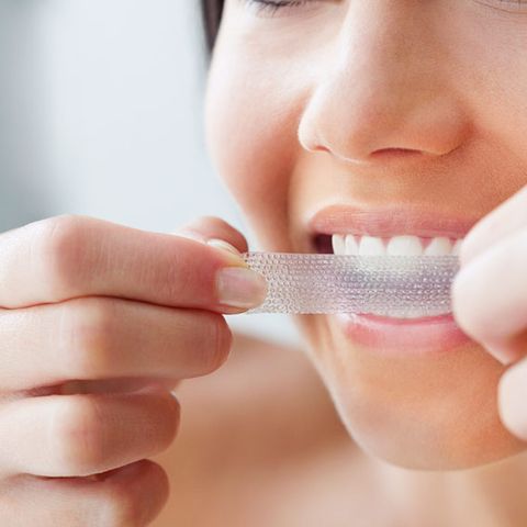 woman using teeth whitening strips