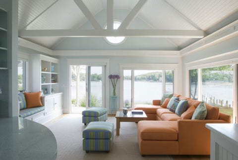 living room with orange couch and big windows next to lake