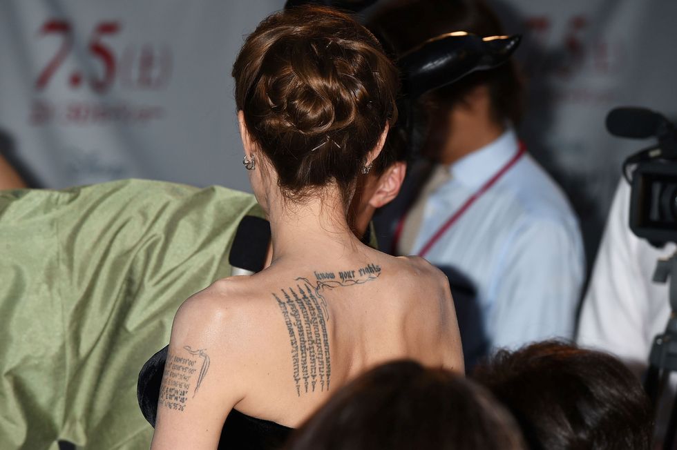 <p>In Thailandia Angelina Jolie si è fatta tatuare cinque righe verticali in lingua Khmer per proteggere i suoi figli, sulla spalla sinistra, mentre più centrale, tra le scapole, è presente la scritta 'know your rights'. Sempre a Bangkok l'attrice si è regalata una tigre del Bengala nella parte bassa della schiena (che copre parzialmente altri disegni), e negli ultimi tempi negli 'spazi vuoti' tra le scapole che vedete nella foto sono comparsi dei nuovi tatuaggi, tre simboli thai e mantra.</p>