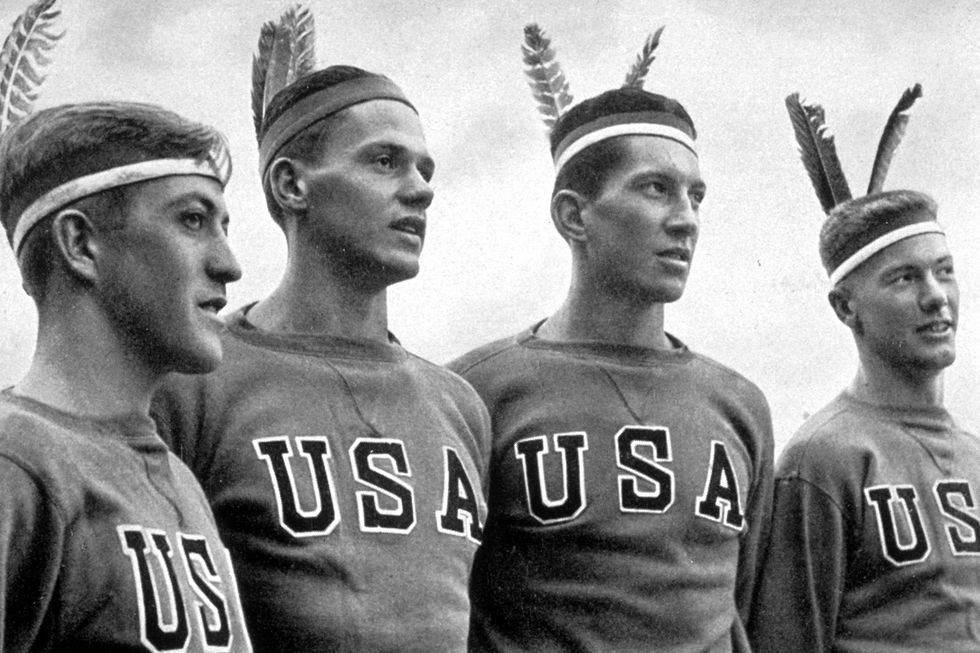 August 1936:  Four American athletes wearing Indian headresses watching their fellow athletes at the 1936 Berlin Olympics.  (Photo by Hulton Archive/Getty Images)