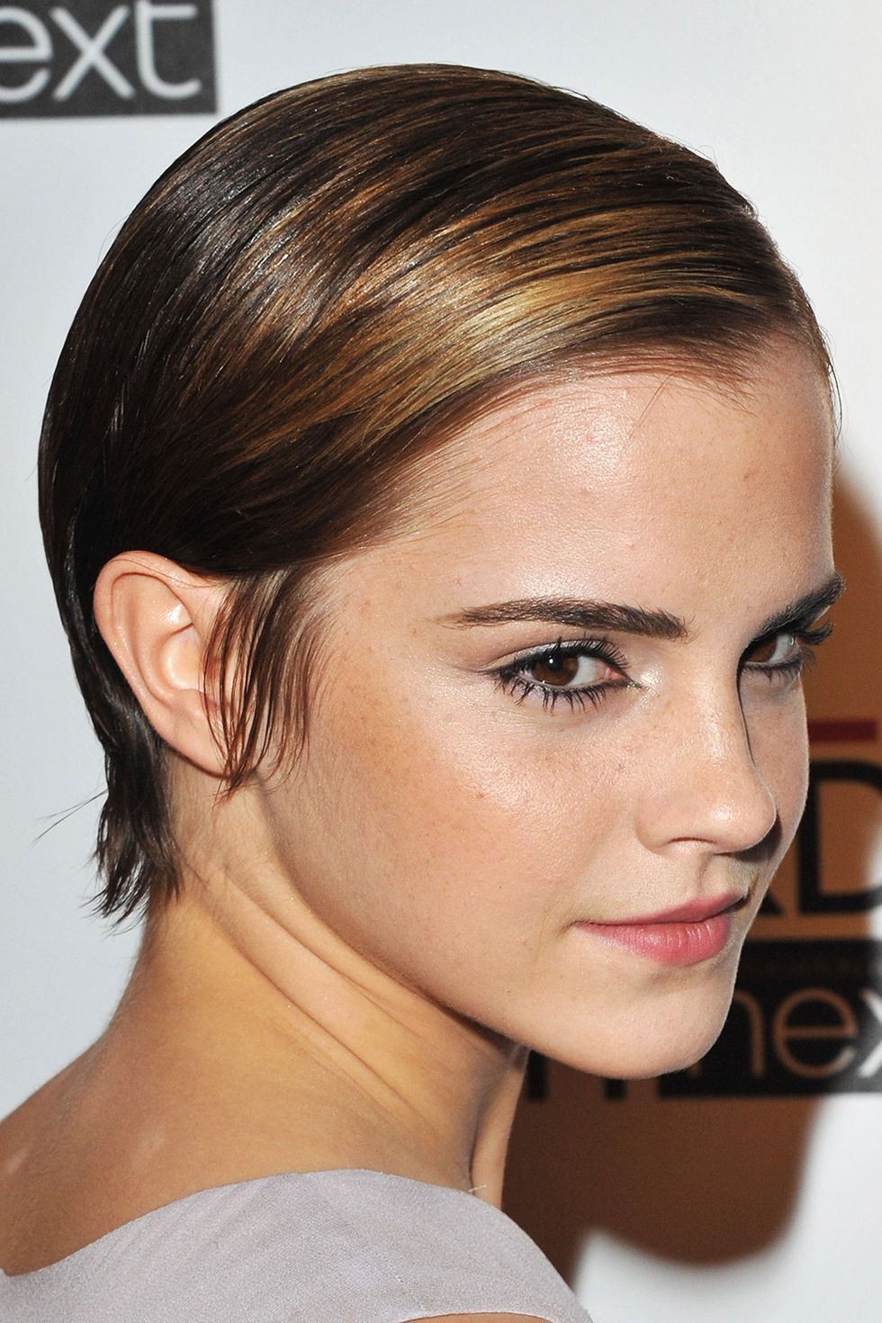 <p>Watson proves just how versatile short hair can be with this slicked-back and shiny style.</p>