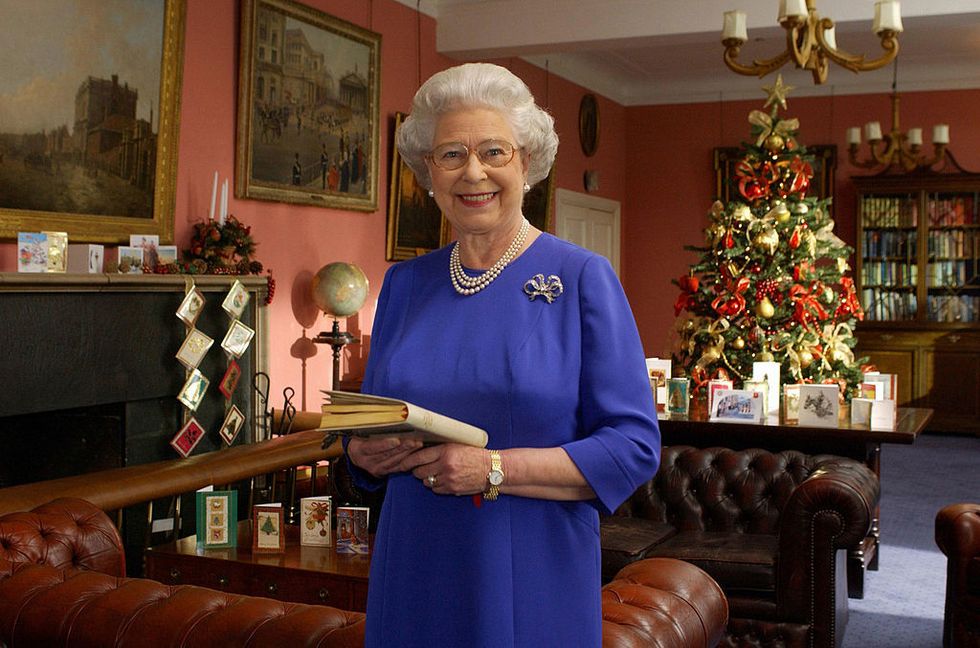 <p>As we can see in this 2001 photo, Queen Elizabeth displays the thoughtful cards on every surface available — from the mantel, to sofa tables, to her coffee table. We also love how the tree's red and gold decorations pick up the color in the room, along with the clever use of ribbon to display even more cards on the mantel.</p>
