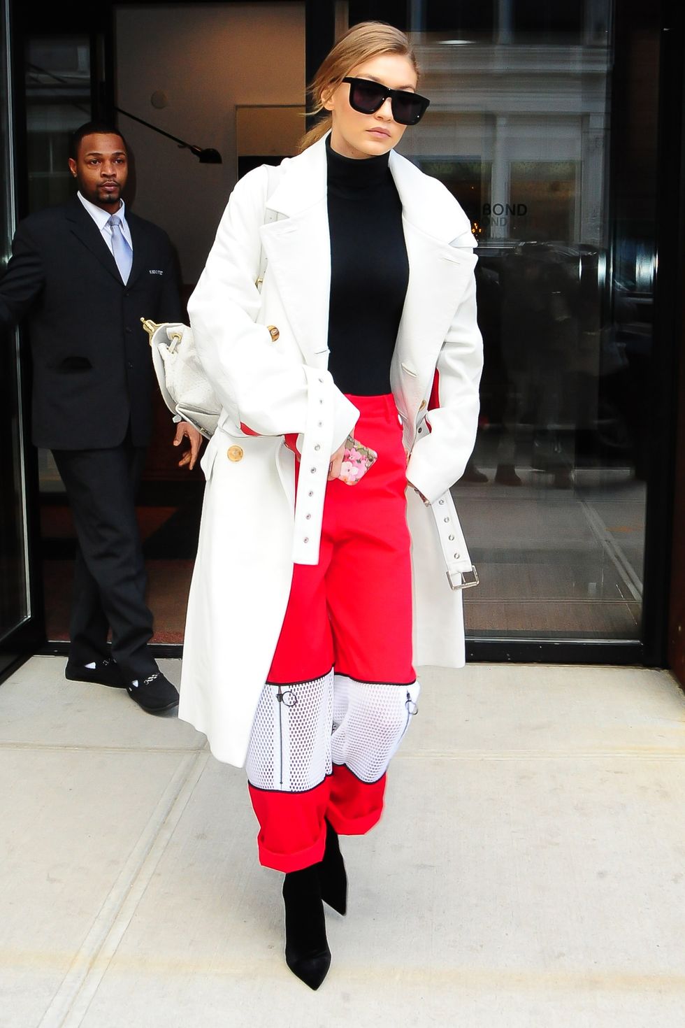 <p>Pantaloni rossi con zip decorative, cappotto bianco, dolcevita nero, &nbsp;ankle boots neri e occhiali Karen Walker.&nbsp;</p>