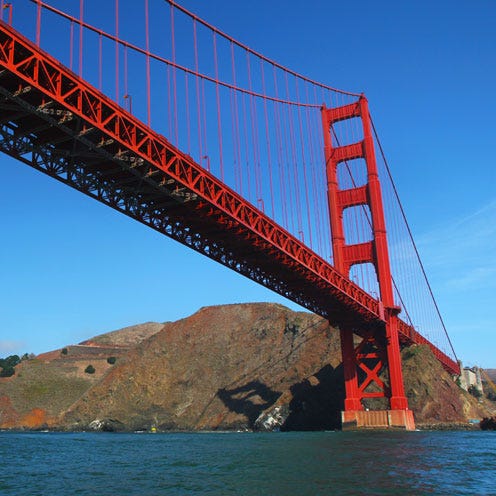Body of water, Coastal and oceanic landforms, Sky, Bridge, Water, Suspension bridge, Red, Waterway, Landmark, Horizon, 