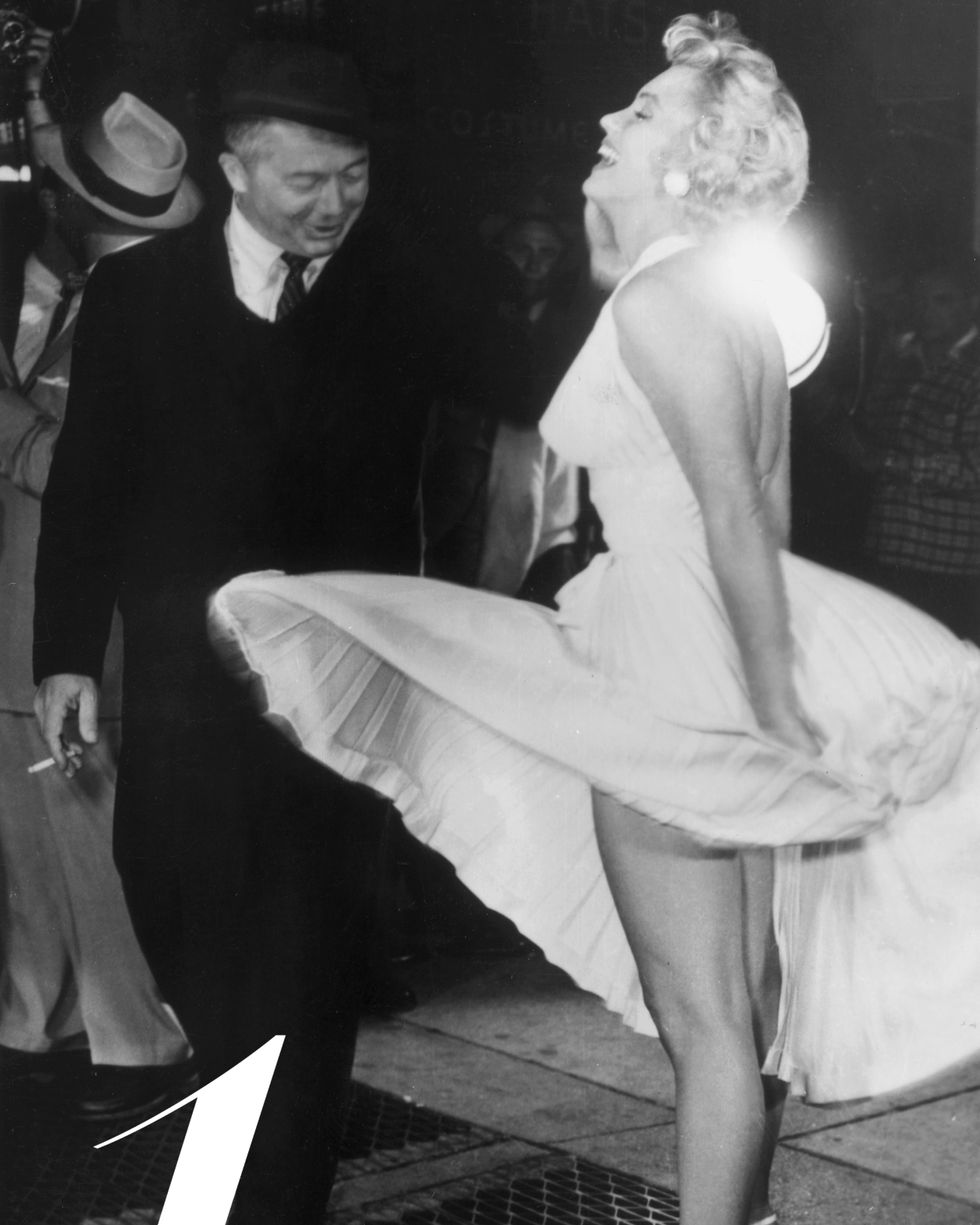 1955:  American actor Marilyn Monroe stands on a subway grate and laughs as the wind blows the skirt of her white halter dress next to Austrian-born director Billy Wilder (1906 - 2002) on the set of Wilder's film, 'The Seven Year Itch' Times Square, New York City.  (Photo by Hulton Archive/Getty Images)