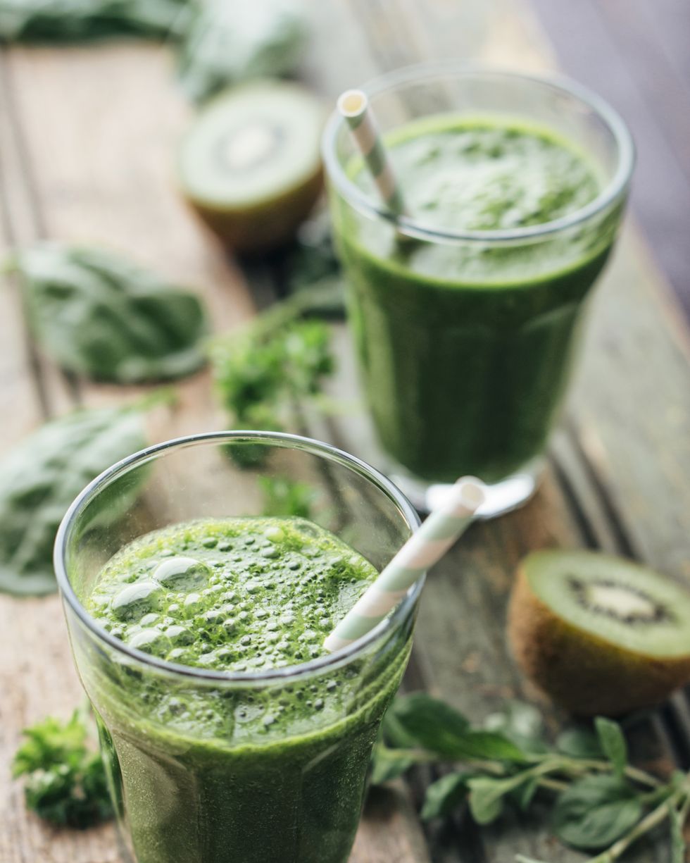 Green vegetable and fruit smoothie with spinach, salad, parsley, cress, oregano and kiwi