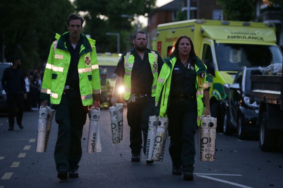 Paramedics carry oxygen tanks by Grenfell Tower in West London
