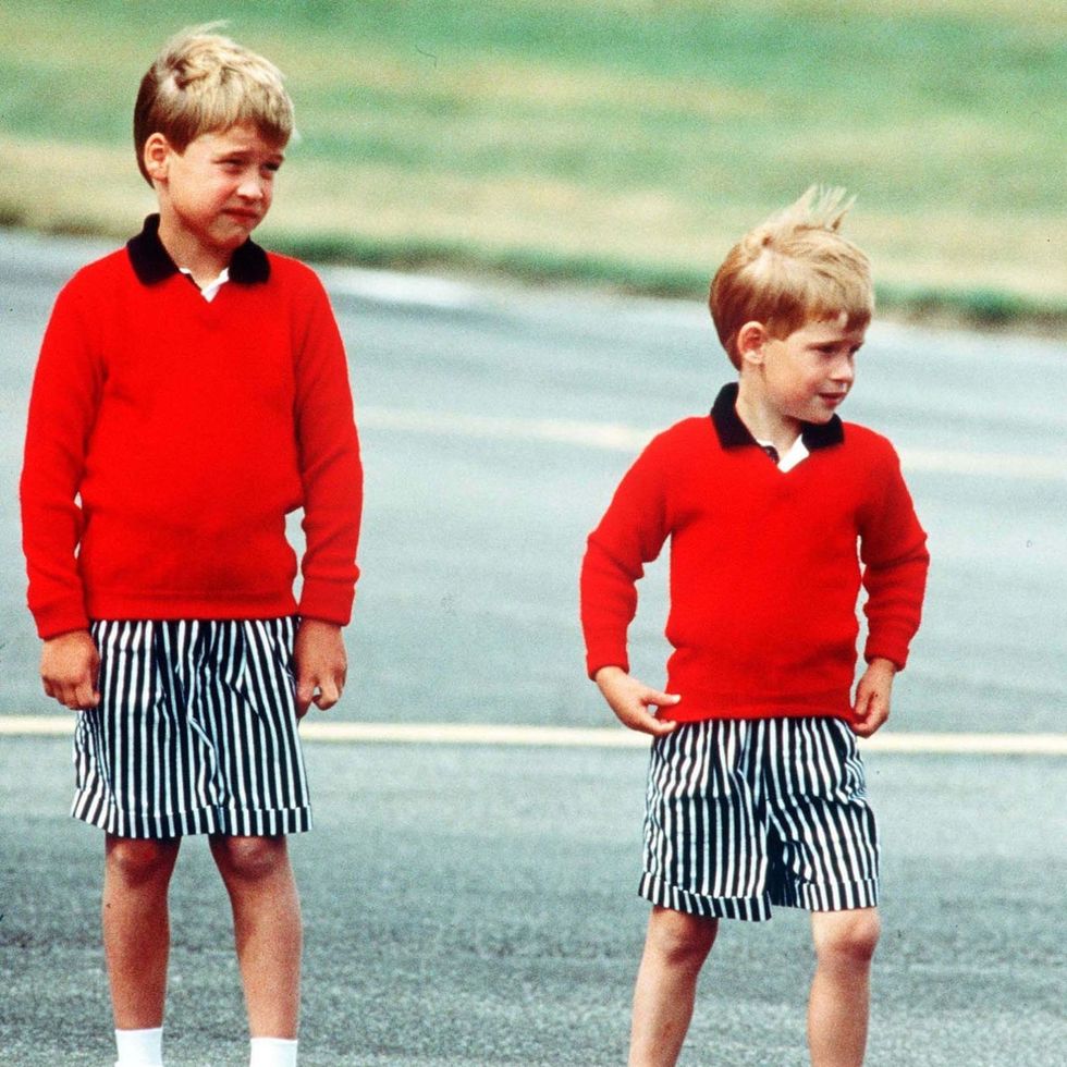 Prince William, Prince Harry Prince William and Prince Harry, wearing identical red jumpers and stripey shorts, arrive at Aberdeen Airport at the start of their holidays in Scotland in August 1989 in Aberdeen, Scotland. (Photo by Anwar Hussein/Getty Images)