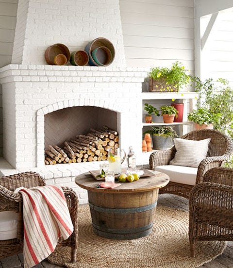The combination of California weather and a fireplace makes this outdoor living area a year-round hangout. Wicker chairs from a local shop surround the coffee table, fashioned out of a reclaimed wine barrel. The walls are painted Sherwin Williams Collonade Gray. Fireplace is painted Benjamin Moore China White. #outdoor #fireplace #decoratingideas