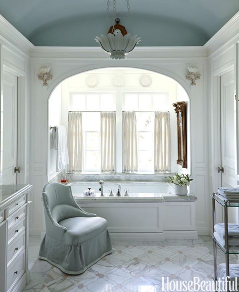 Błyszczący beczkowy sufit w głównej łazience jest pomalowany farbą Skylight firmy Farrow Ball. Armatura wanny firmy P.E. Guerin. Krzesło DeAngelis w tkaninie Empress Satin firmy Fret Fabrics.