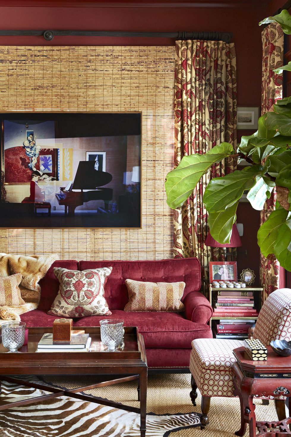 "Not￼￼hing transports like a deep red room," says McDonald of the sumptuous library. The window was covered with a bamboo shade to create an artful backdrop for the photograph by Augusta Wood. Walls in Benjamin Moore's Classic Burgundy. A Vaughan side table holds a lamp by Visual Comfort; a zebra-patterned hide tops a Stark rug.