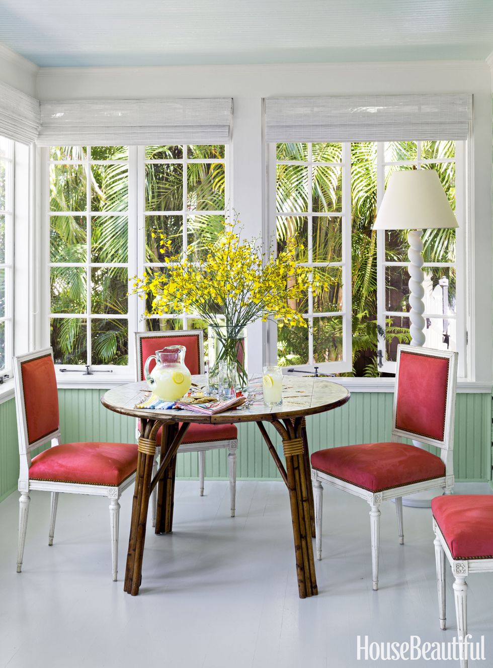 todd romano florida house dining room with red chairs and rattan table