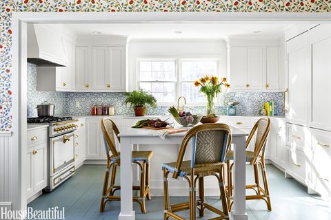<p>In the kitchen, white cabinetry sets off a backsplash in Mosaic House's Batha Moroccan tile. A trio of Ballard Designs Paris Bistro stools pull up to a Corian-topped island and a fireclay farmhouse sink by Rohl has a brass Waterworks Easton faucet.</p>