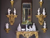 entryway with dark painted wall and gold sconces with white figurines