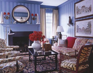 Blue sitting room with flowered sofas and red flowers.