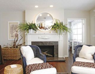 wall mirror above fireplace in room with two chairs