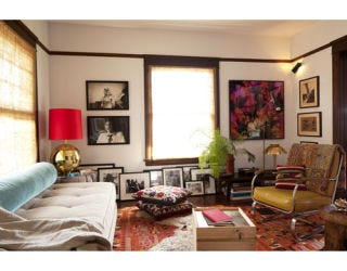 living room with photos hung on walls and propped against the wall and red carpeting