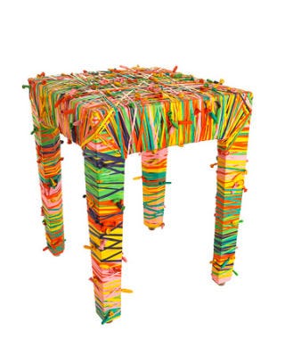 four legged square stool covered in brightly colored tied balloons