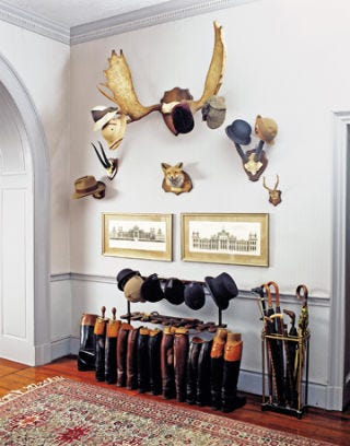 entryway with boots and antlers with hats hanging from them