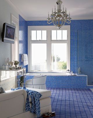 blue tiled bathroom with tv and chandelier