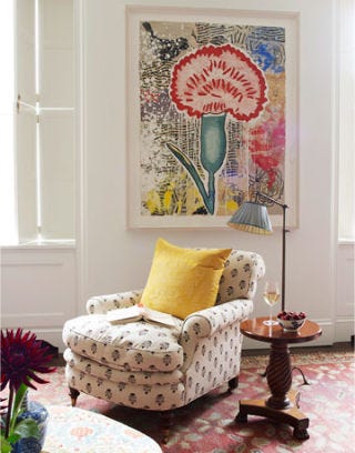 pink flower painting above comfy reading chair and lamp