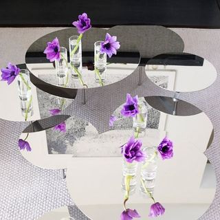 circular mirrored tables with purple flowers in water on top